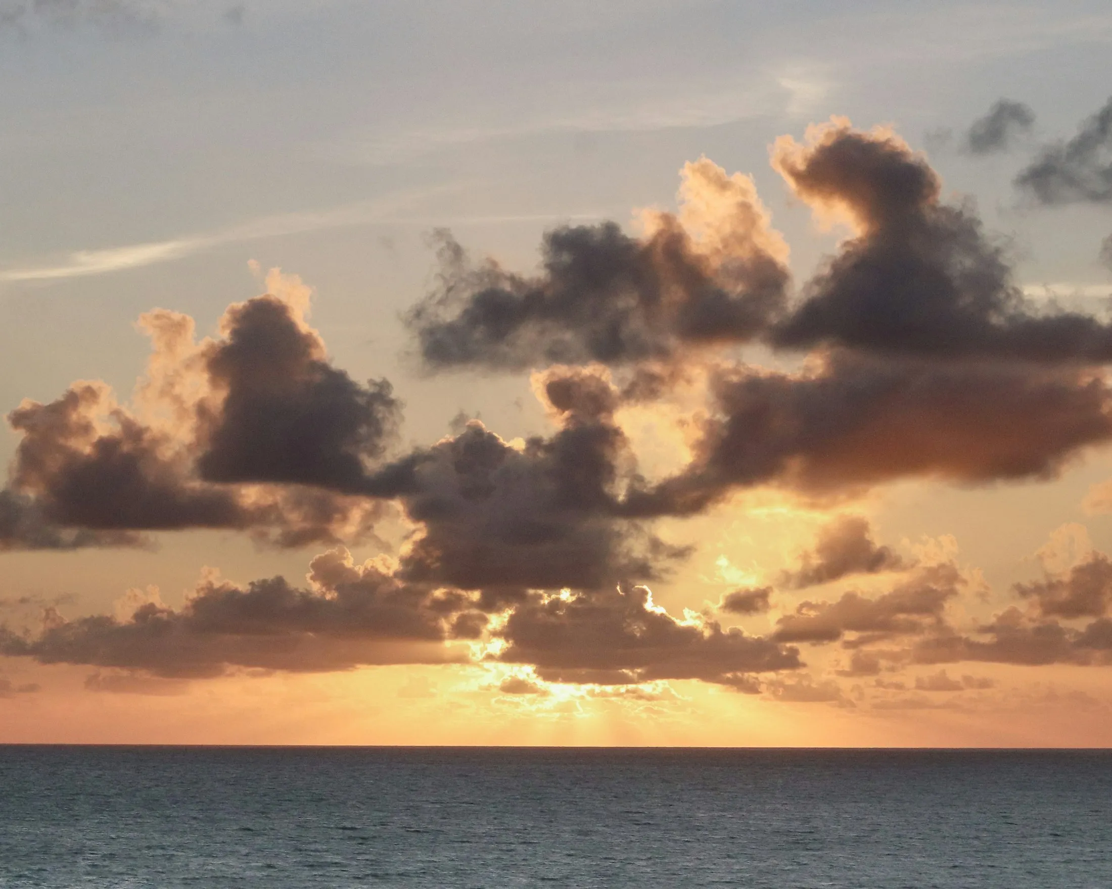 Pôr do sol sobre o mar com nuvens douradas